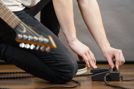 Man with musical instrument setting up guitar audio stomp box effects and cables in music studioの写真素材