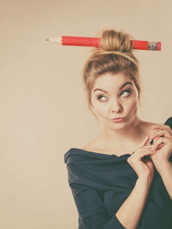 Charming thinking blonde woman having big pencil in hair having something on her mind, education ideas.の写真素材