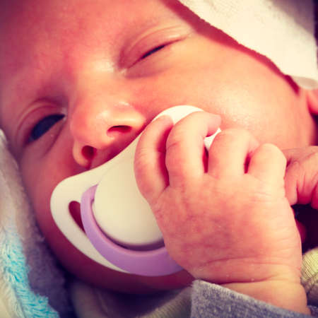 Infant care, beauty of childhood concept. Little newborn baby sleeping calmly in bed with teat in...