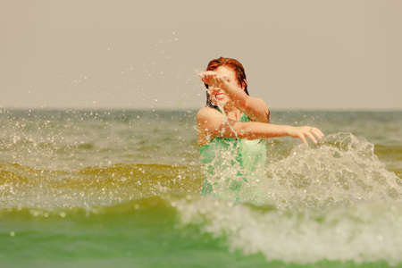 Summer fun, recreation outside concept. Redhead adult woman playing in water during summertime,...
