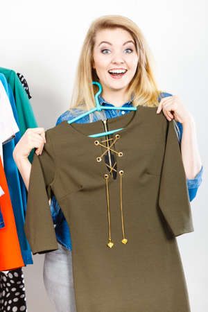 Happy young woman during shopping time picking clothes for perfect fashionable outfit holding green...