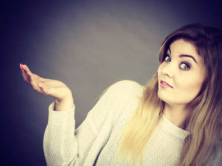 Confused young blonde woman gesturing with hands. Confusion face expressions concept. Studio shot on...