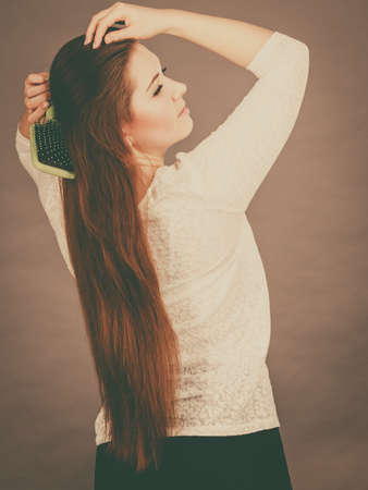 Haircare and morning hairstyling concept. Happy woman brushing her long dark brown hairの写真素材