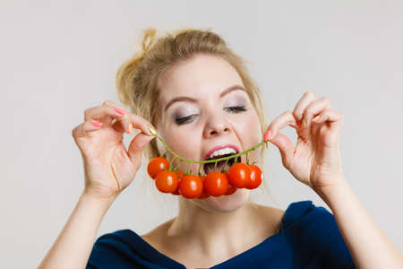 Organic vegetables and food concept. Happy positive smiling woman holding fresh cherry tomatoesの写真素材