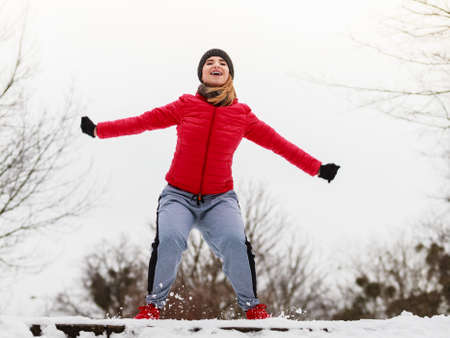 Outdoor sport exercises, sporty outfit ideas. Woman wearing warm sportswear training exercising outside during winter, jumping out of joy.の写真素材
