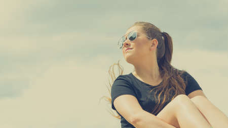 Young beautiful teenage woman spending her leisure time outside relaxing during summertime warm weather enjoying herself.の写真素材