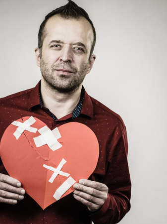 Bad relationships, breaking up, sadness emotions concept. Adult man holding broken heart, on greyの写真素材
