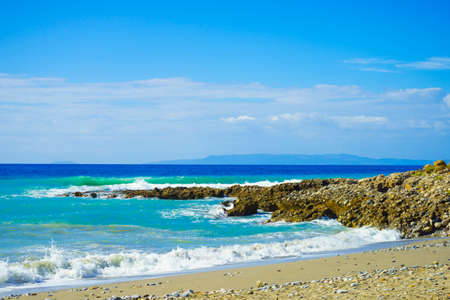 Beautiful sandy beach coastline next to sea edge with water waving and splashing during summertime...