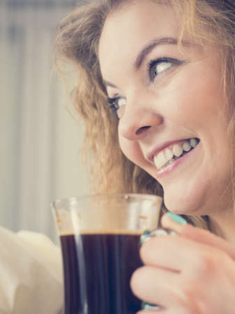 Positive woman holding black coffee about to drink. Getting morning energy, hurry up before going to work.の写真素材