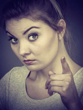Young attractive woman pointing into camera, teenage judging someone. Studio shot on grey background.の写真素材