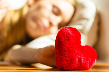 Sad lonely woman lying on bed being alone with heart shape.の写真素材