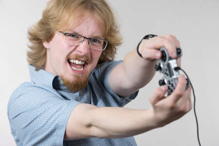 Nerd geek young adult man playing on the video console holding game pad. Gaming gamers concept.