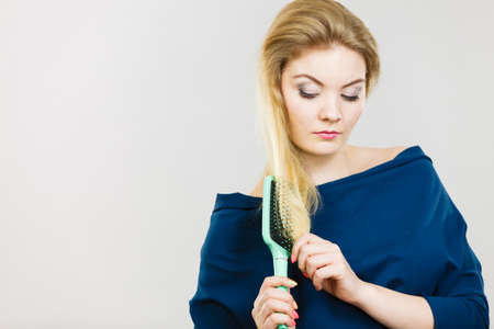 Woman combing her hair with brush. Young female with beautiful natural blond straight long hairs,...