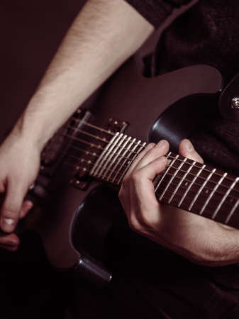 Male hands with electric guitar. Close up, part body adult person is holding instrument and playing. Hobby, music conceptの写真素材