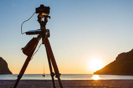 Professional camera taking picture film video of scenic orange sunrise or sunset over sea surface, Greece Peloponnese.の写真素材