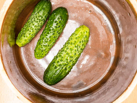 Preparing sour low salt cucumbers in clay jar pot. View from aboveの写真素材