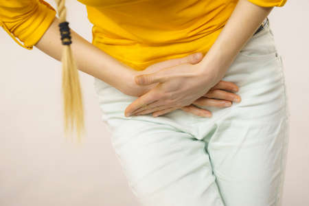 Closeup young sick woman with hands holding pressing her crotch lower abdomen. Medical or gynecological problems, healthcare conceptの写真素材