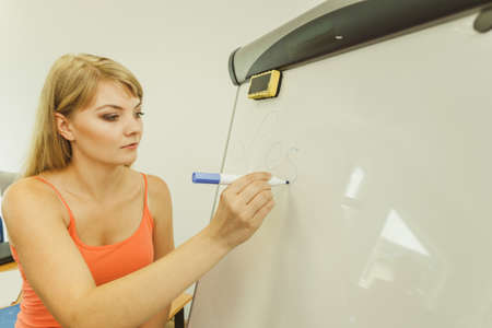 Education, teaching and learning concept - Young woman with marker writing word lesson on whiteboardの写真素材