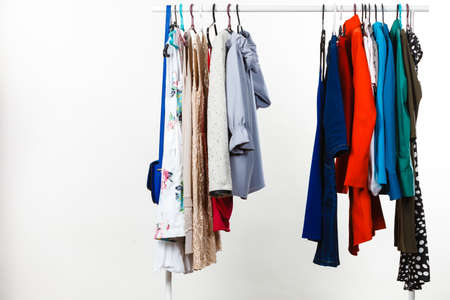 Wardrobe furniture concept. Many clothes on hangers in closet. Studio shot on grey background.