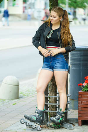 Teenage woman girl riding roller skates during summertime through city having great time.