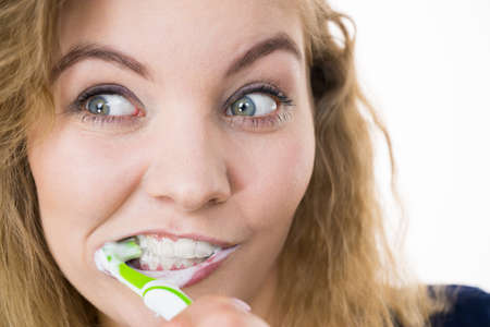 Woman brushing cleaning teeth. Positive girl with toothbrush. Oral hygiene. Studio shot on white backgroundの写真素材