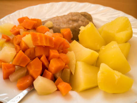 Close up of food an plate. Dinner meal, braised carrot, boiled potatoes and meatの写真素材