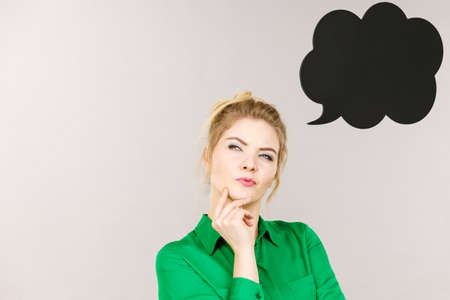 Business woman wearing green jacket and eyeglasses intensive thinking finding great problem solution, black thinking or speech bubble next to her.の写真素材