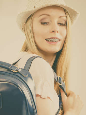 Happy young blonde teenage girl going to school or college wearing backpack.の写真素材