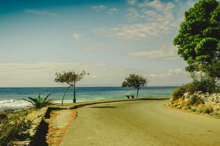 Sunny promenade during summertime weather in warm climate country. View at see and tropical trees.の写真素材