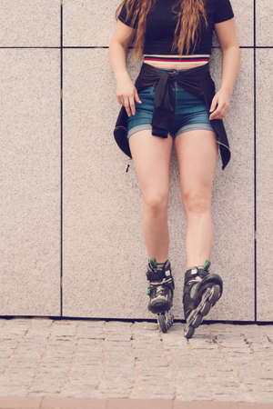 Sexy woman slim legs wearing roller skates standing outside. Sport activity concept.の写真素材