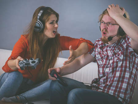 Couple enjoying leisure time by playing video games together, man and woman being shocked by game.の写真素材