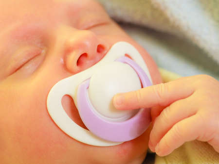 Infant care, beauty of childhood concept. Little newborn baby sleeping calmly in bed with teat in...