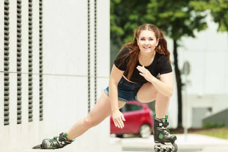Teen woman wearing roller skates riding fast in city. Female being sporty having fun during summer time.の写真素材