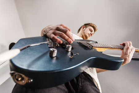 Young bearded man with electric guitar. Adult person is holding instrument and playing. Hobby, music...