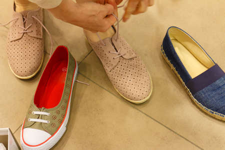 Unrecognizable woman trying on new shoes, getting comfortable in shop buying and choosing best...
