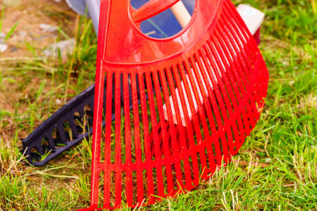 Gardening tools. Orange rake and broom on green grass lawn, garden equipmentの写真素材