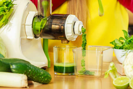 Drinks good for health, diet breakfast concept. Woman in kitchen making green healthy vegetable smoothie juice from green vegetablesの写真素材