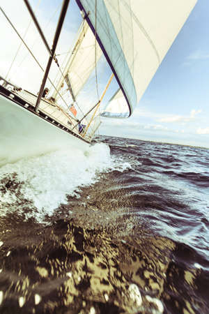 Yachting on sail boat bow stern shot splashing sea water. Sporty transportation conept.の写真素材