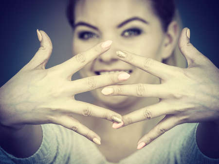 Happy proud young woman showing her hands in front of her face, studio shot grey background.の写真素材