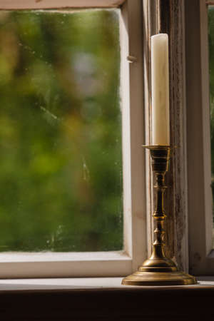 Old vintage objects, wood concept. Old vintage window and vertical candle in candlestickの写真素材