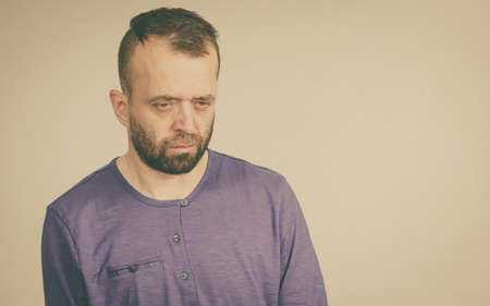 Very sad and worried adult man. Guy being depressed looking down. Studio shot.