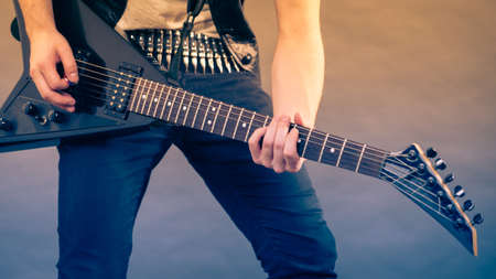 Male hands with electric guitar. Close up, part body adult person is holding instrument and playing. Hobby, music conceptの写真素材