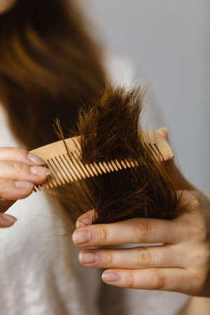 Woman trying to brush dry tangled hair ends. Healthy haircare and hairstyling concept.の写真素材