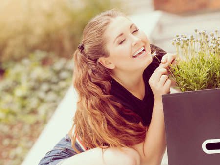 Close up of happy woman smelling wild flowers. Female being with natureの写真素材