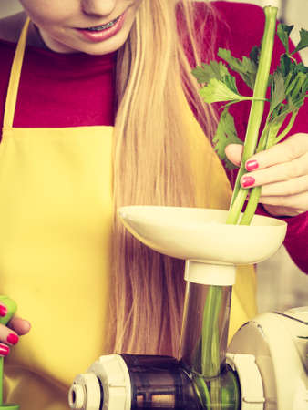 Drinks good for help, diet breakfast concept. Young woman in kitchen making green healthy vegetable smoothie juice from green vegetablesの写真素材