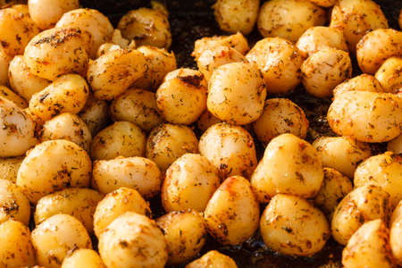 Healthy food concept. Backed young potatoes with spices and seasonings in black bowlの写真素材