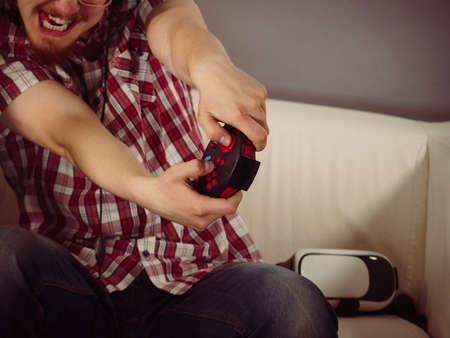 Nerd geek young adult man playing on the video console holding game pad. Gaming gamers concept.