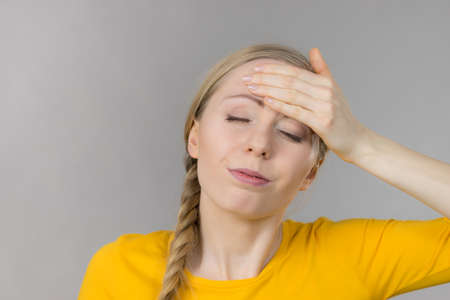 Young blonde woman having serious migrene suffering from horrible head ache feeling big pain.