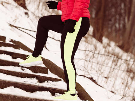 Outdoor sport exercises, sporty outfit ideas. Woman wearing warm sportswear training exercising stretching legs outside during winter. Cityscape panorama in backgroundの写真素材