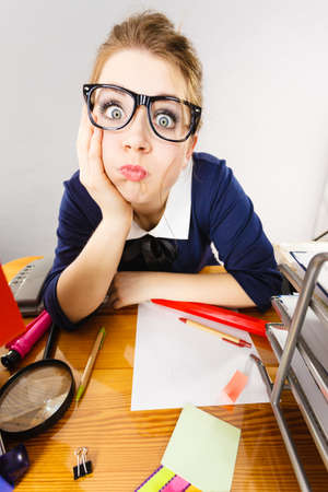 Sleepy business woman doing her work sitting working at desk full off documents in binders being bored or tired staying up late.の写真素材